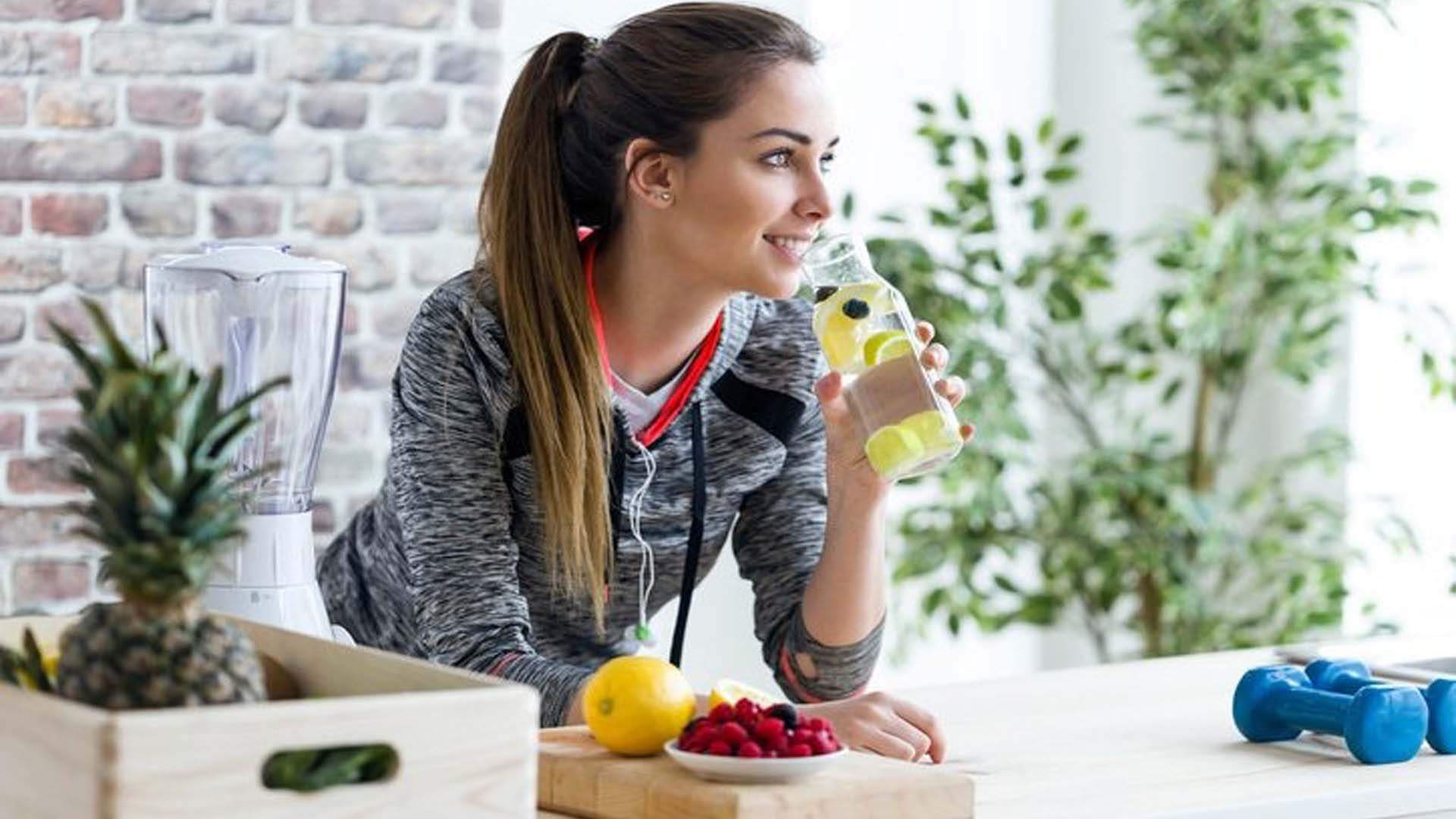 A woman holding a water bottle filled with lemons