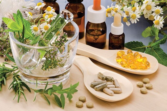 Naturopathic capsules on the wooden spoons and herbs